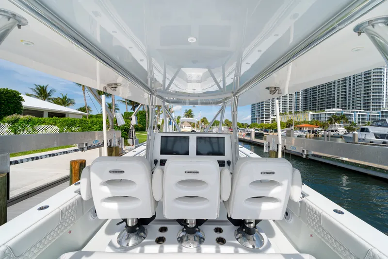 Slide: The Image of 2026 Contender 44 ST boat interior with white seating and modern dashboard at marina. - 21