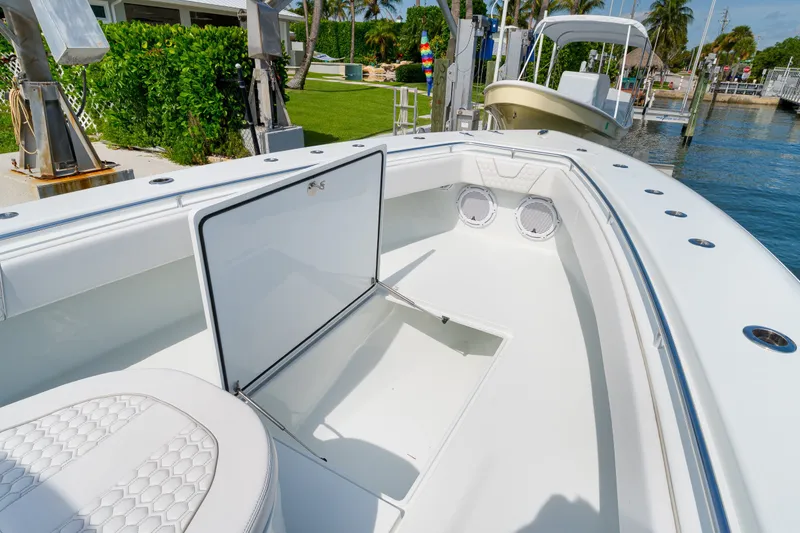 Slide: The Image of 2026 Contender 44 ST boat interior with open storage compartment, docked near lush greenery. - 24