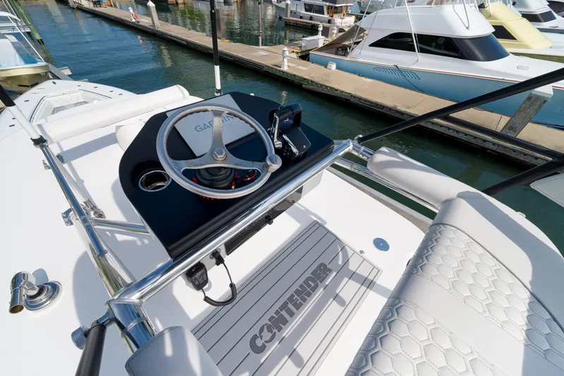 Slide: The Image of 2026 Contender 44 ST boat helm with steering wheel and Garmin controls at marina. - 33