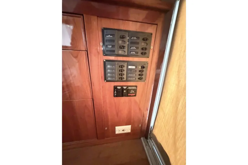 Slide: The Image of Electrical panel inside a 2000 Riviera 48 Convertible yacht, featuring wooden cabinetry. - 15