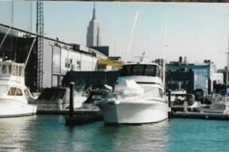 Slide: The Image of Riviera 48 Convertible yacht docked in a marina with city skyline backdrop. - 21