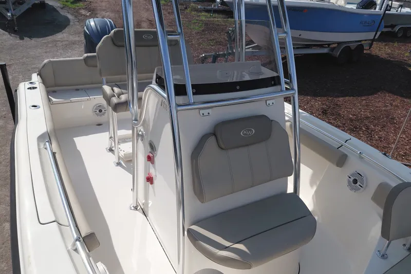 Slide: The Image of 2024 Key West 219 FS boat interior with seating and console, docked outdoors. - 36