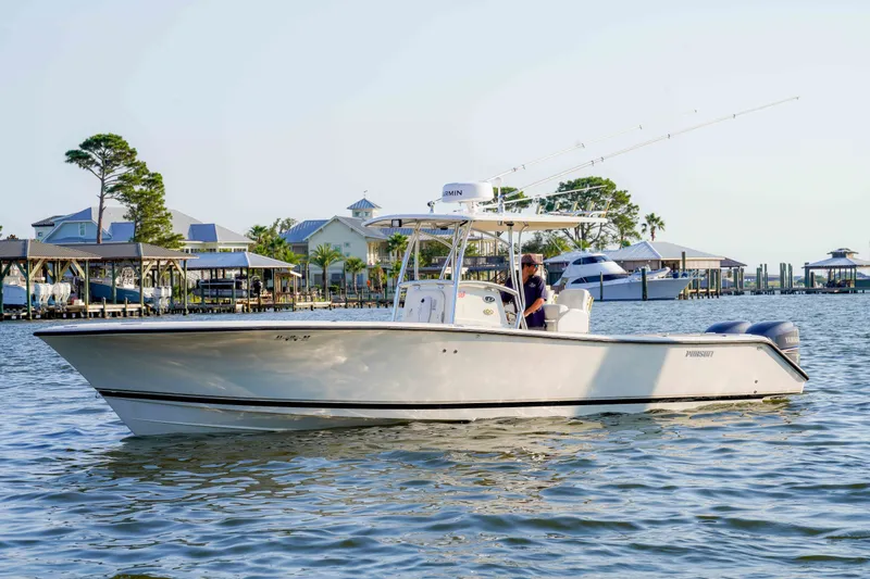 Slide: The Image of 2005 Pursuit 3480 Center Console boat cruising on calm waters near a marina. - 6
