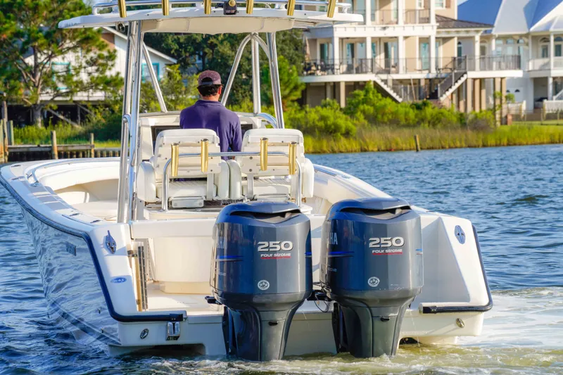 Slide: The Image of 2005 Pursuit 3480 Center Console boat cruising on a scenic waterway near waterfront homes. - 13