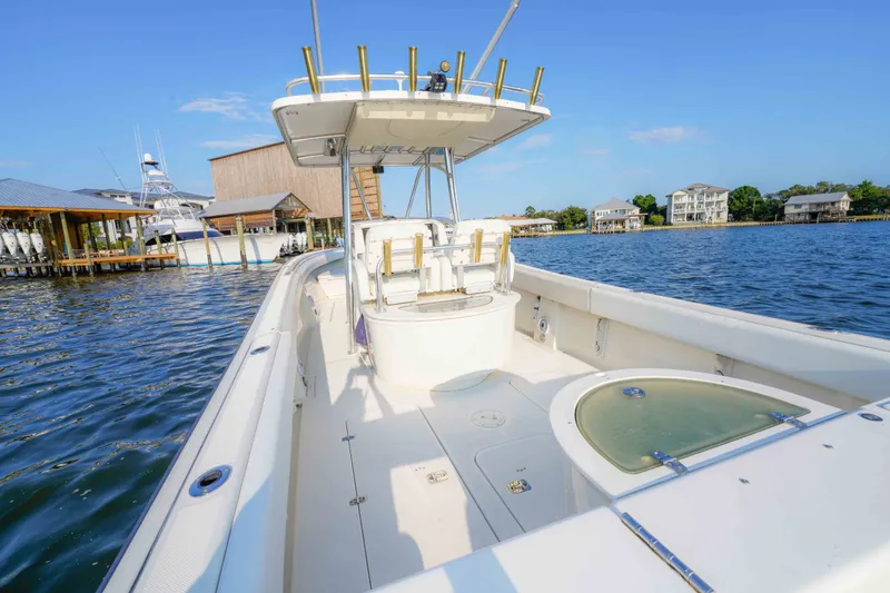 Slide: The Image of 2005 Pursuit 3480 Center Console boat docked by waterfront homes under clear blue sky. - 22