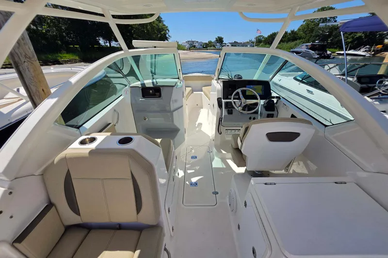 Slide: The Image of 2021 Pursuit DC 266 Dual Console boat interior with seating and helm, docked by the shore. - 15