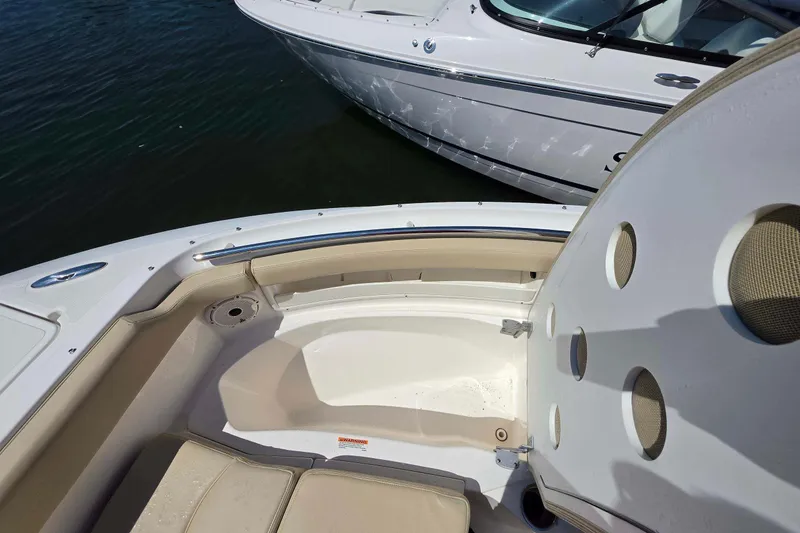 Slide: The Image of 2021 Pursuit DC 266 Dual Console boat interior with seating and storage, docked on water. - 23