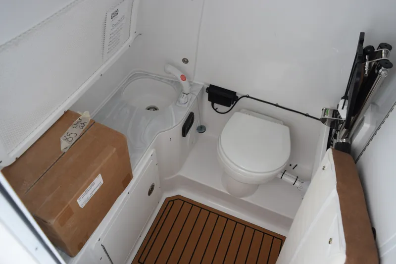 Slide: The Image of 2027 Sea Hunt Ultra 285SE boat bathroom with toilet, sink, and storage box. - 16