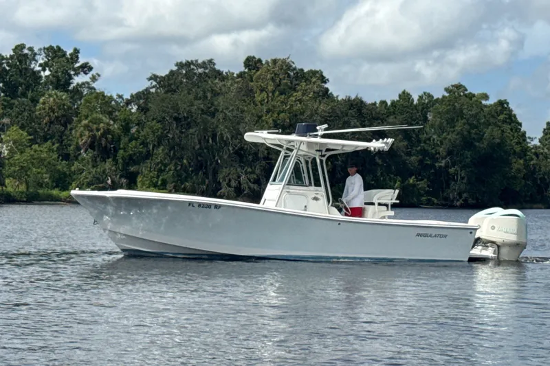 Slide: The Image of 2007 Regulator 26 Classic boat on calm water with lush green trees in the background. - 26