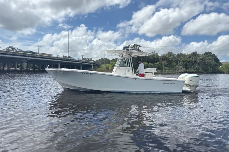 The Image of 2007 Regulator 26 Classic boat on a calm river under a cloudy sky. - 0