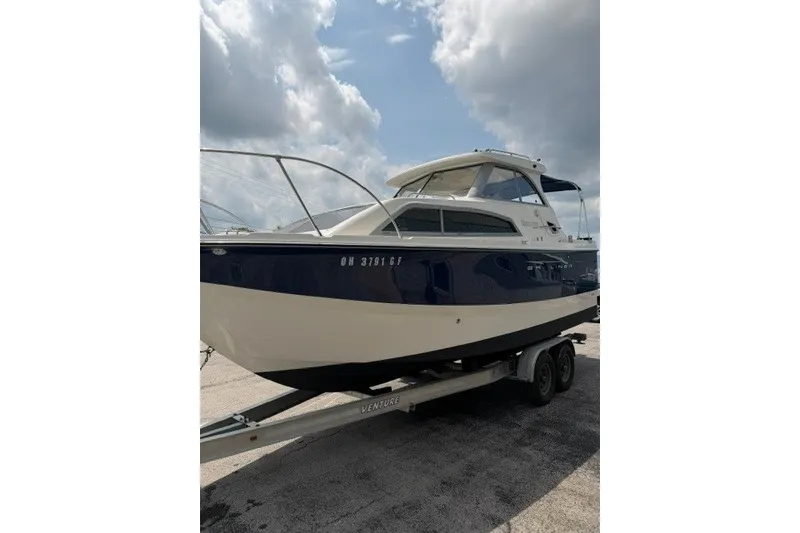 Slide: The Image of 2007 Bayliner Discovery 246 boat on trailer under cloudy sky. - 2
