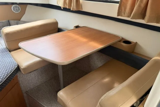 Slide: The Image of 2007 Bayliner Discovery 246 interior with dining table and beige seating. - 6