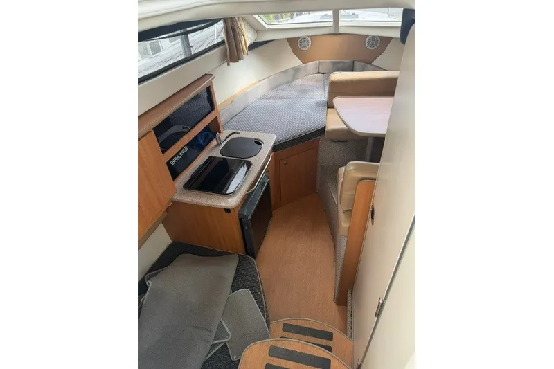 Slide: The Image of 2007 Bayliner Discovery 246 cabin interior with kitchenette, seating, and sleeping area. - 7