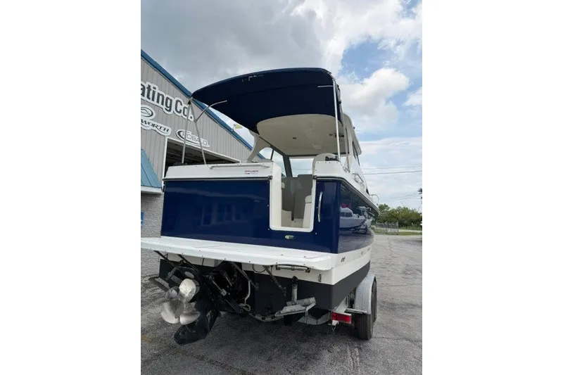 Slide: The Image of 2007 Bayliner Discovery 246 boat, blue and white, parked on a trailer under a cloudy sky. - 17