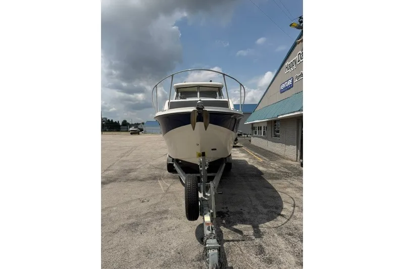 Slide: The Image of 2007 Bayliner Discovery 246 boat on trailer, parked outside dealership under cloudy sky. - 3