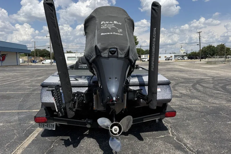 Slide: The Image of 2018 Skeeter FX21 boat with covered motor, parked in a lot under a cloudy sky. - 13