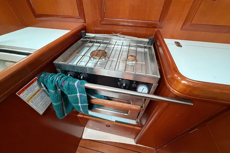 Slide: The Image of Compact kitchen stove in a 2001 Beneteau 331 sailboat galley, featuring wooden cabinetry. - 24