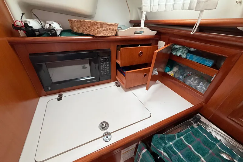 Slide: The Image of 2001 Beneteau 331 yacht galley with microwave, storage cabinets, and wooden finish. - 23