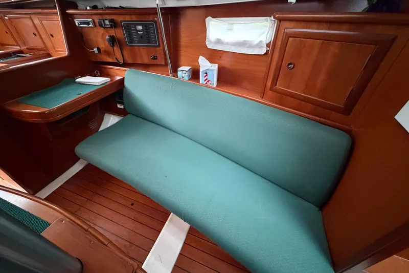 Slide: The Image of Interior of 2001 Beneteau 331 sailboat with teal seating and wooden cabinetry. - 12