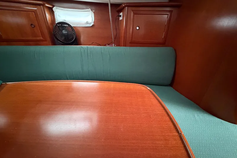 Slide: The Image of Interior of 2001 Beneteau 331 sailboat with wooden table and green seating. - 11