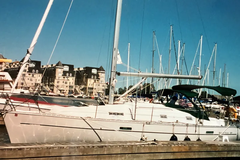 The Image of Sailboat Beneteau 331, 2001 model, docked in a marina with buildings in the background. - 1
