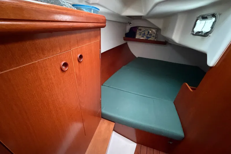 Slide: The Image of Cozy cabin interior of 2001 Beneteau 331 sailboat with wooden cabinetry and green cushions. - 28