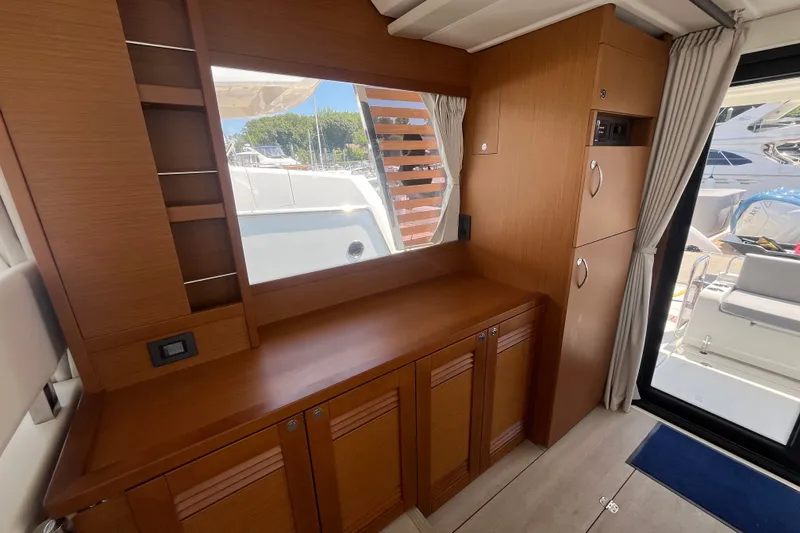 Slide: The Image of Interior of 2026 Beneteau Swift Trawler 41 Fly, featuring wooden cabinetry and window view. - 15