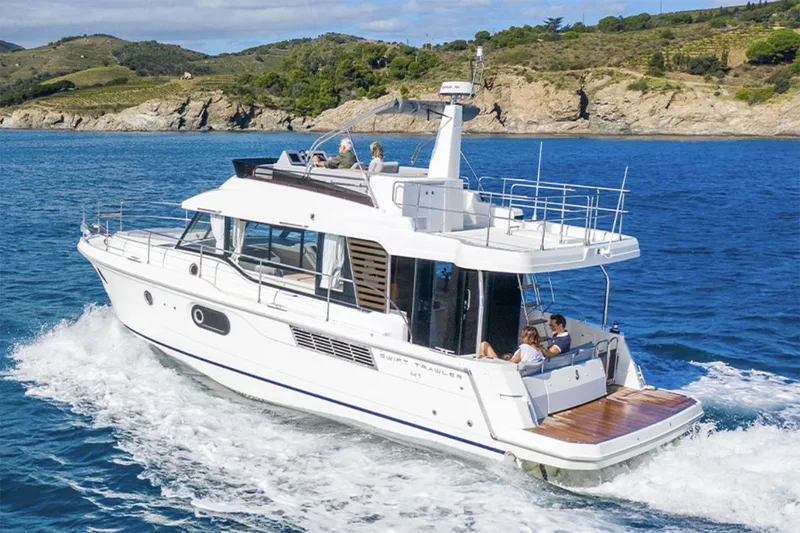 The Image of Manufacturer Provided Image: 2026 Beneteau Swift Trawler 41 Fly cruising on blue ocean near rocky coastline. - 0