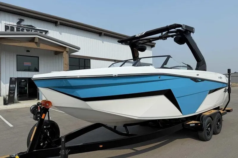 The Image of 2027 Tigé Z3 boat with blue and white design on a trailer outside a building. - 1
