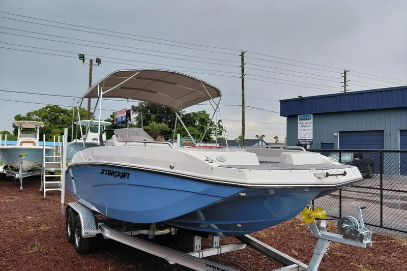 The Image of 2027 Starcraft SVX 211 OB boat on trailer, parked outside a marine dealership. - 1