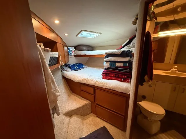 Slide: The Image of The cabin of a 1997 Ocean Yachts 40ss features bunk beds, cabinets, and a small bathroom. - 13