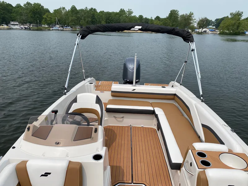 Slide: The Image of The image shows a 2027 Starcraft 211SVXOB boat on a calm lake. It features beige and white seating with a black sunshade. - 4