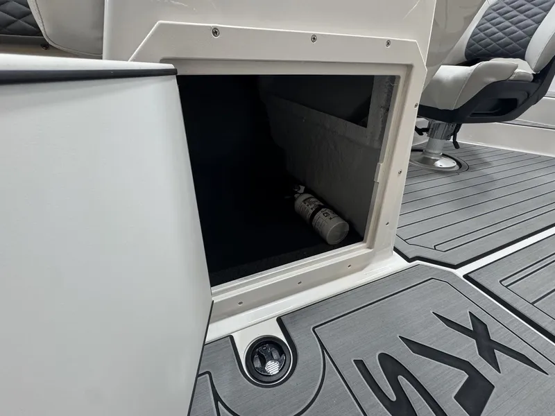 Slide: The Image of An open storage compartment on a boat with gray flooring and a seat in the background. - 28