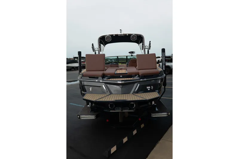 Slide: The Image of 2020 MasterCraft XT25 boat with brown seating, rear view in a parking lot. - 8