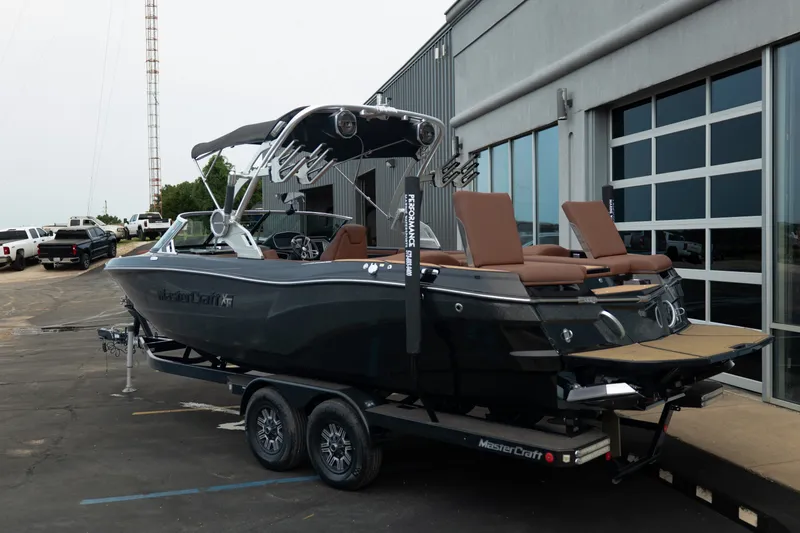 Slide: The Image of 2020 MasterCraft XT25 boat on trailer, parked outside a modern building. - 7