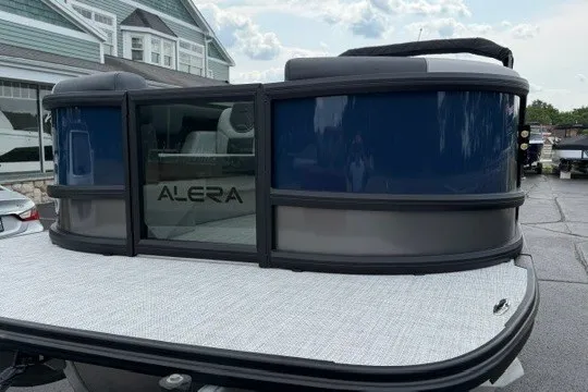 Slide: The Image of 2027 Alera M25Q pontoon boat with sleek blue and gray design, docked outdoors. - 6