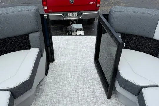 Slide: The Image of Alera M25Q 2027 boat interior with gray seating and open gate, red truck in background. - 62