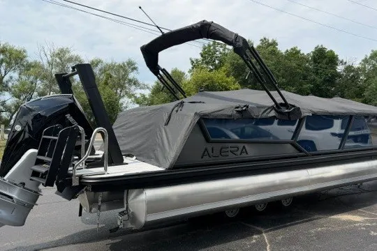 Slide: The Image of 2027 Alera M25Q pontoon boat with cover, parked outdoors. - 84