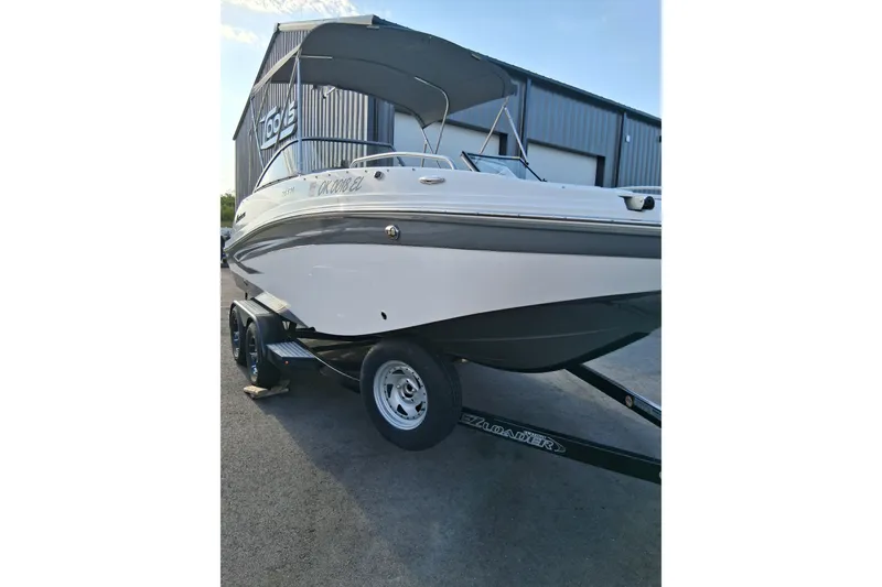 Slide: The Image of 2024 Hurricane SunDeck 191 OB boat on trailer, parked outside a metal building. - 7