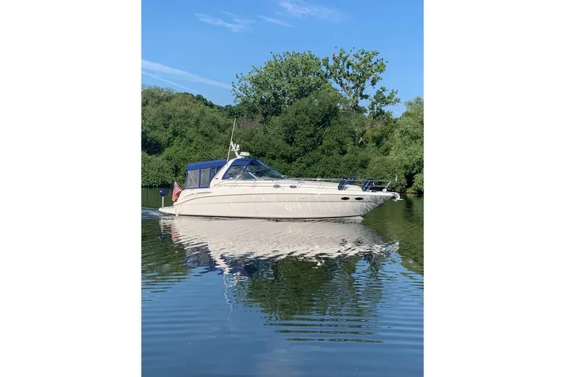 Slide: The Image of 2000 Sea Ray 380 Sundancer yacht on calm water, surrounded by lush greenery. - 1