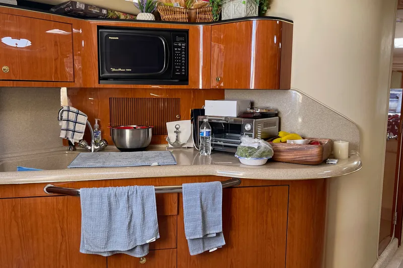 Slide: The Image of Galley kitchen in a 2000 Sea Ray 380 Sundancer yacht with wooden cabinetry and modern appliances. - 28