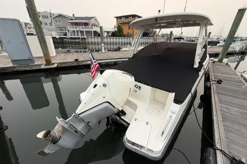 Slide: The Image of 2022 Boston Whaler 240 Vantage boat docked, covered, with outboard motor and American flag. - 60