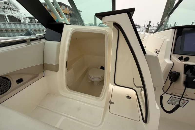 Slide: The Image of 2022 Boston Whaler 240 Vantage boat interior with open cabin door revealing a compact toilet. - 32