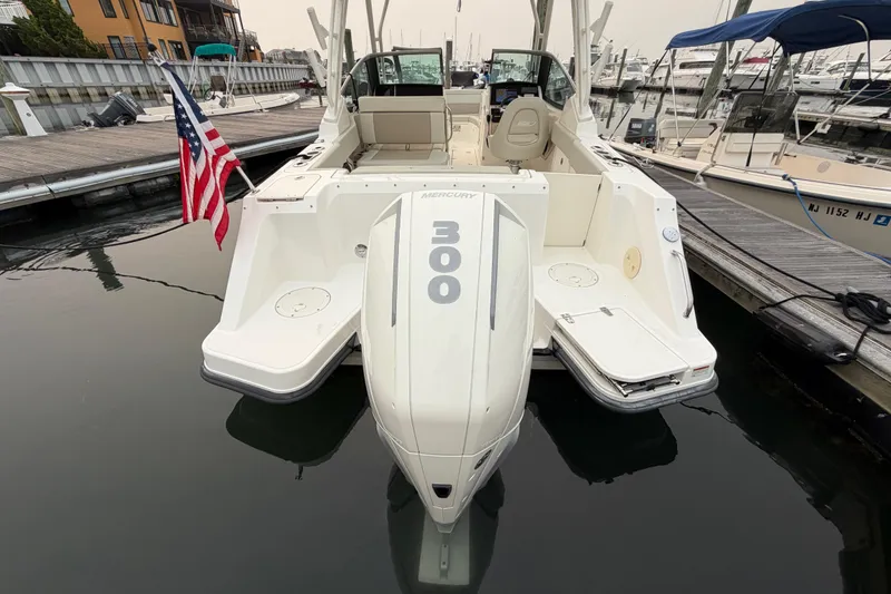 Slide: The Image of 2022 Boston Whaler 240 Vantage boat docked, featuring a Mercury 300 engine and American flag. - 55