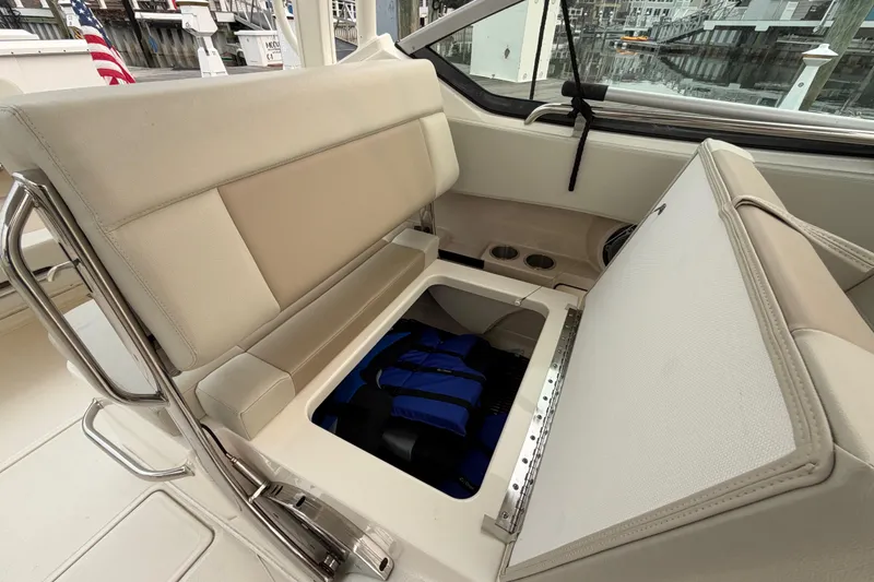 Slide: The Image of Boston Whaler 240 Vantage 2022 boat seat with storage compartment open, revealing life jackets. - 42