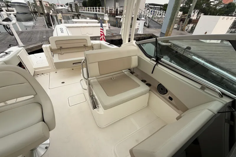 Slide: The Image of 2022 Boston Whaler 240 Vantage boat interior with beige seating at dock. - 21