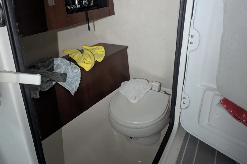 Slide: The Image of Interior of 2018 Robalo R227 Dual Console boat with compact bathroom amenities. - 15