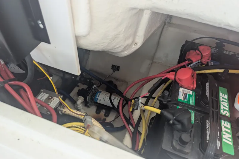 Slide: The Image of A view inside the engine compartment of a 2018 Robalo R227 Dual Console boat with batteries and wiring. - 19