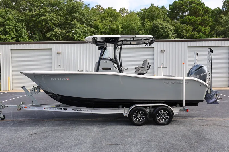 Slide: The Image of 2020 Sea Pro 239 Center Console boat on trailer, parked near industrial building. - 5