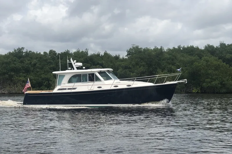 The Image of 2021 Back Cove 41 yacht cruising on a calm river with lush greenery in the background. - 1